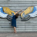 woman dancing in front of wings painting